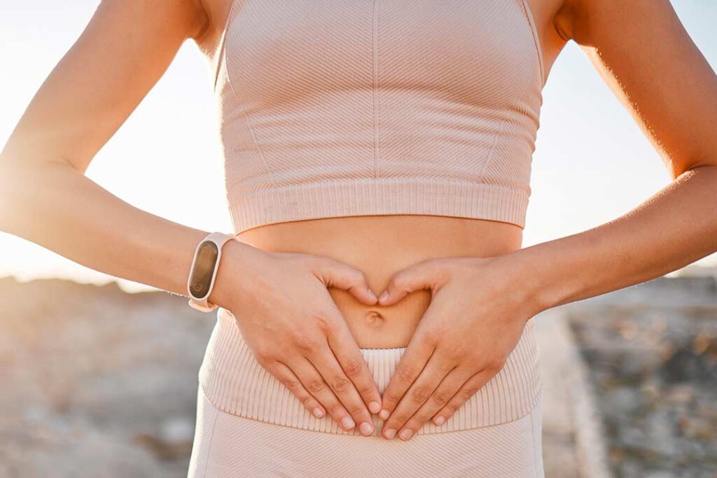 Mujer haciendo un corazón con la mano sobre el estómago para indicar bienestar gastrointestinal.